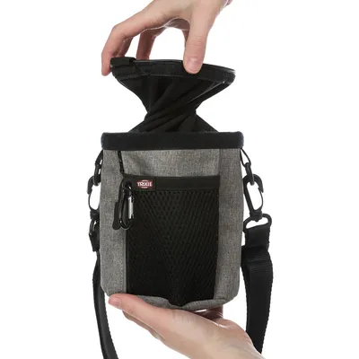 Sacoche grise Trixie avec poche filet noire, bandoulière et fermeture à cordon, tenue par une main, ouverture du dessus visible.