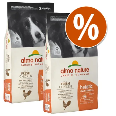 Dos sacos de pienso para perros Almo Nature Holistic Maintenance con pollo fresco, 12 kg, texto en varios idiomas y símbolo de porcentaje en círculo naranja.