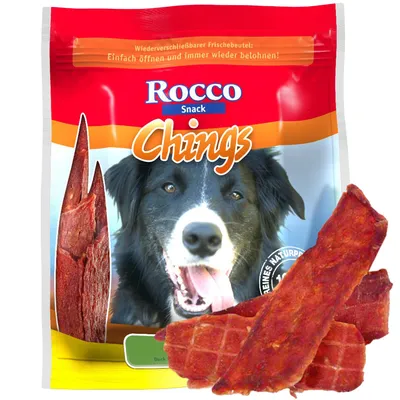 Rocco Snack Chings, balení s obrázkem psa a plátky sušeného masa, viditelný text: Wieder verschließbarer Frischebeutel: Einfach öffnen und immer wieder belohnen!