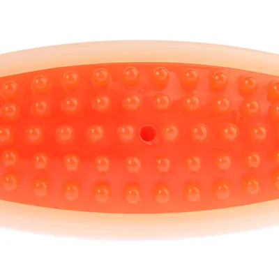 Close-up of an orange massage or grooming tool with a nubbed texture and a small hole in the centre.