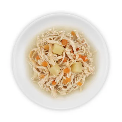 Nærbillede af hakket kyllingekød med gulerods- og kartoffelstykker i bouillon, serveret på en hvid tallerken.