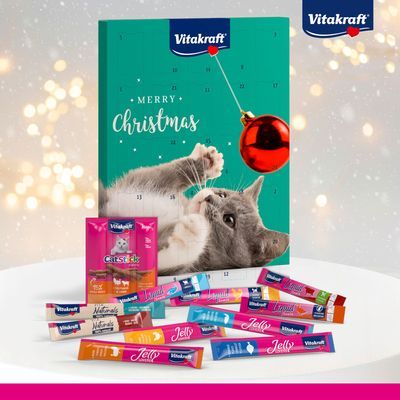 Vitakraft adventskalender met kat, tekst 'Merry Christmas', diverse Vitakraft kattensnacks in sticks en zakjes zichtbaar voor de kalender. Merknaam Vitakraft op verpakking.