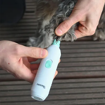 Elektrisk kloslip från Kerbl används på en hunds tass. Vit och mintgrön apparat med synlig strömbrytare och varumärket Kerbl tryckt på handtaget.