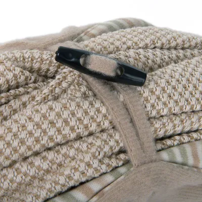 Close-up of beige patterned fabric with black plastic buckle and hook-and-loop fastener.