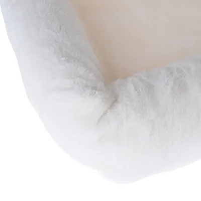 Primer plano de un material blanco y esponjoso, posiblemente parte de una cama para mascotas o una manta.