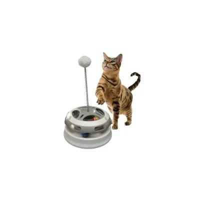 Chat tigré debout à côté d’un jouet interactif rond en plastique avec balle sur ressort et balles colorées à l’intérieur du socle.