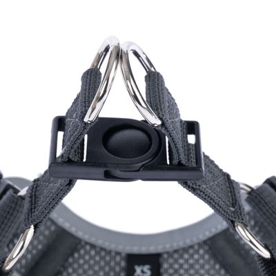 Vista dettagliata di una pettorina grigia con due anelli in metallo e una chiusura in plastica nera, taglia XS visibile.