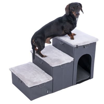 Psia schodíková rampa s tromi stupňami, sivý textilný poťah a mäkký povrch. Spodný stupeň s integrovaným úkrytom. Jazvečík stojí na najvyššom stupni.