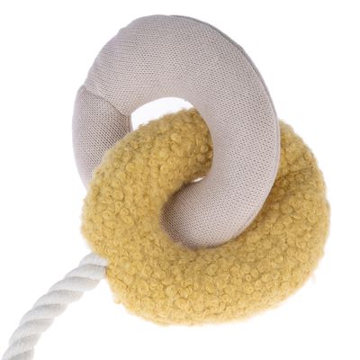 Jucărie din material textil cu două inele împletite, unul galben și pufos, celălalt bej și neted, unite printr-o frânghie albă.