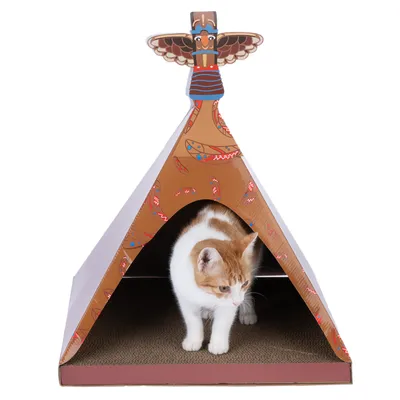 Cat house in tipi shape made of cardboard with colourful feather pattern and totem pole decor, cat standing in the entrance.