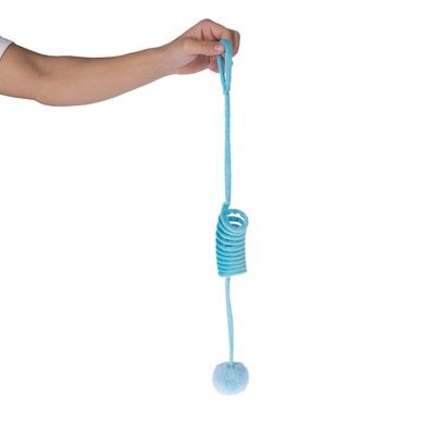 Mano sostiene juguete azul con espiral elástica y bola de felpa en el extremo.