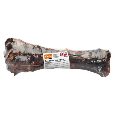 Os de bœuf séché emballé, étiquette visible : Karlie, Dried beef underpaw, sans gluten, 1 pièce. Texte en anglais sur la composition et les informations du produit.