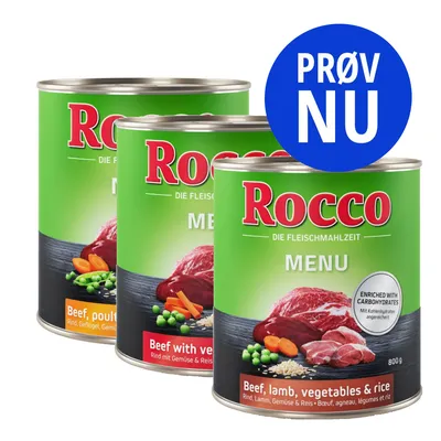 Tre dåser Rocco MENU hundemad, synlig tekst: 'Beef, lamb, vegetables & rice', 'Beef with vegetables', 'PRØV NU', 800 g. Billeder af kød, grøntsager og ris på etiketterne.