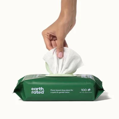 Earth Rated roślinne chusteczki dla psów, 100 sztuk, rozmiar 20x20 cm. Ręka wyciąga chusteczkę z opakowania do szybkiego i delikatnego czyszczenia.
