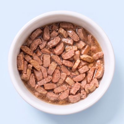 Ciotola con pezzi di carne marrone in gelatina o salsa, primo piano di alimento umido.