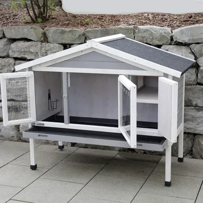 Weisses Kleintierhaus mit zwei Türen, Gitterfenster und schwarzem Dach. Innenraum mit Ablage und Zubehörhalterung. Geeignet für Aussenbereich.