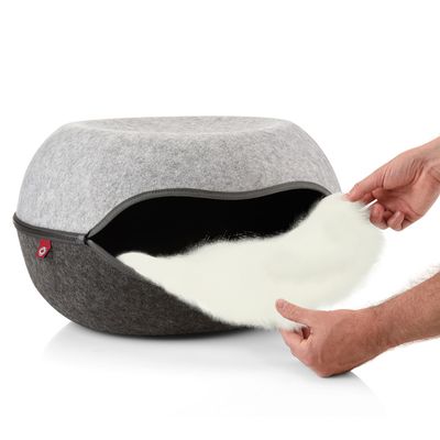 Letto per pet rotondo grigio con cuscino interno bianco rimovibile. Mani che rimuovono il cuscino.