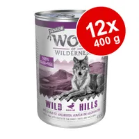 Wolf of Wilderness Senior Wild Hills våtfoder, 100% grain-free, 12x400 g. Text: Anka & kalv med skogsbär, rötter och vilda örter. Bild på varg och bergslandskap.