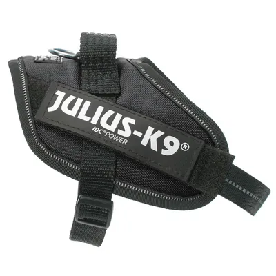 Črna oprsnica iz tkanine z napisom JULIUS-K9 IDC®POWER, vidna sponka in trak za zapenjanje.