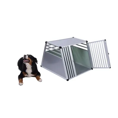 Transportbox van metaal met traliewanden en open deur, geschikt voor huisdieren. Hond zit ernaast en kijkt omhoog.