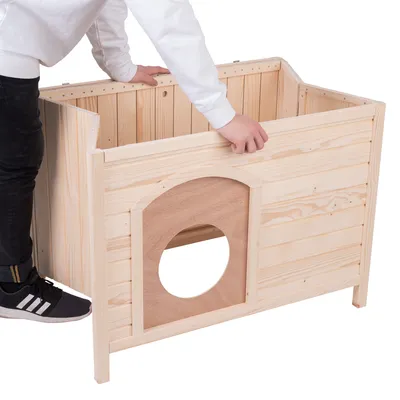 Montaža lesene hišice z odstranljivo sprednjo ploščo in okroglim vhodom. Oseba prikazuje namestitev plošče.