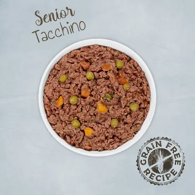 Ciotola con alimento umido per animali, visibili piselli e carote. Testo: Senior Tacchino. Marchio: Grain Free Recipe.