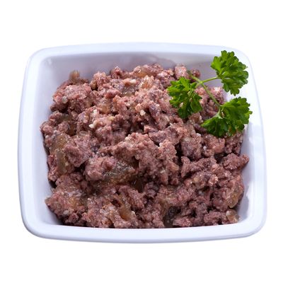 Keraaminen valkoinen kulho, jossa ruskeaa märkäruokaa ja persiljan oksa koristeena päällä.