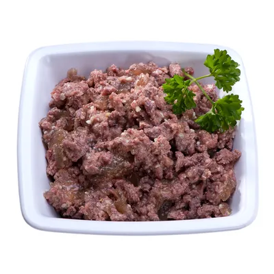 Keraaminen valkoinen kulho, jossa ruskeaa märkäruokaa ja persiljan oksa koristeena päällä.