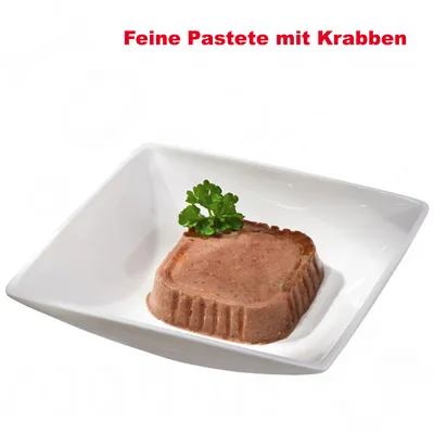 Pâté fine con granchio, servita in una ciotola bianca, decorata con un rametto di prezzemolo verde.