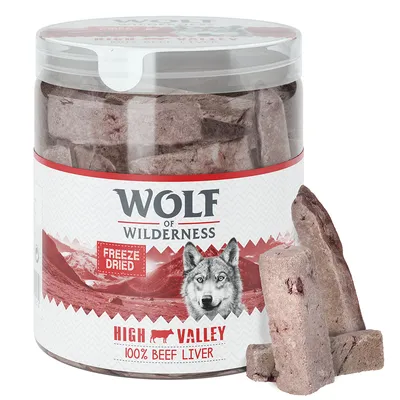 Plastikbeholder med Wolf of Wilderness frysetørret High Valley 100% beef liver. Synlige stykker okselever foran beholderen. Tekst: Freeze Dried, High Valley, 100% Beef Liver.