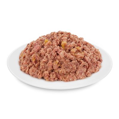 Apróra vágott, darált állagú nedves állateledel fehér tányéron, látható hús- és zöldségdarabokkal. Csomagolás vagy márkanév nem látható.