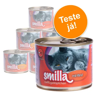 Várias latas de comida para gato Smilla Geflügeltöpfchen, visível texto 'mit Rind', 'mit Lamm', 'mit Taurin' e selo laranja com 'Teste já!'. Imagem de um gato cinzento nas embalagens.