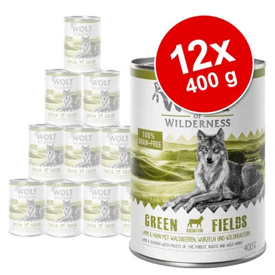 Pack de 12 latas de 400 g Wolf of Wilderness Green Fields Senior, sin cereales, con imagen de lobo y texto visible: '100% grain-free', 'Green Fields', 'Lamb & Chicken with fruits'. Pack de 12 latas de 400 g Wolf of Wilderness Green Fields Senior, sin cereales, con imagen de lobo y texto visible: '100% grain-free', 'Green Fields', 'Lamb & Chicken with fruits'.