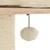 Detalle de poste rascador de sisal con bola de peluche beige colgante sujeta por cuerda negra, base de madera y superficie acolchada visible.