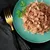 Chunks of meat in jelly served on a green plate with garnish, showing the texture and appearance of the pet food product.