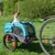 Blauer Fahrradanhänger mit Netzfenstern und Reflektoren, Marke Hafenbande, befestigt an einem Fahrrad. Geeignet für den Transport von Haustieren.
