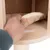 Hand zeigt abnehmbares, gepolstertes Kissen mit Klettverschluss auf einer Holzplattform.