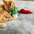 Gatto rosso gioca con gioco di peluche verde e rosso su coperta grigia.