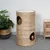 Braided scratching post made from natural material with two round openings and integrated feather toys.