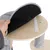 Plateforme en bois clair avec coussin amovible maintenu par une bande auto-agrippante, main soulevant le coussin. Revêtement tissu gris visible sur les poteaux.