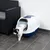 Geschlossene Katzentoilette mit weissem Deckel und blauer Basis, Katze verlässt die Toilette durch die Klapptür.