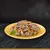 Chunks of meat in gravy with green peas and orange vegetable pieces served on a yellow plate.