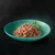 Close-up of tender meat pieces in sauce, served on a green plate with parsley garnish.