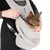 Sac de transport en tissu polaire gris avec sangle, chien marron à l’intérieur, mousqueton de sécurité visible, main tenant le sac. Marque TAK visible sur le sac.