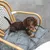 Hund sitzt auf einer grauen, gepolsterten Decke auf einem Stuhl. Produkt zeigt eine tragbare Hundedecke mit Steppdesign.