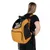 Sac à dos de transport jaune avec fenêtres en maille, porté par une femme, contenant un chat visible à travers l’ouverture latérale.