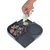 Main versant une pâte depuis un tube sur un plateau d’alimentation en silicone à compartiments texturés, avec pâtée et espace pour l’eau.