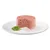 Pâté rosa con erbe verdi, servito su un piatto bianco con una foglia di basilico fresco accanto.