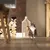 Rascador de sisal con juguete colgante, colocado junto a una pared. Gato sentado al lado mirando hacia arriba.