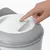 Finger presses the button on a white and grey device with the label 'Catit'. Blue LED indicator is lit.